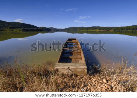 Small old fishing boat in lakeside with fresh nature and blue sky background