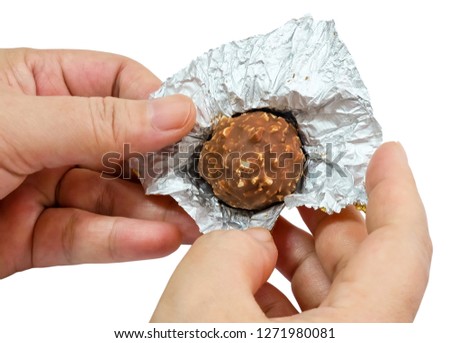 Sweet Food, Hand Opening Round Chocolate Candy Ball or Chocolate Bonbon From The Golden Wrapper Isolated on White Background.