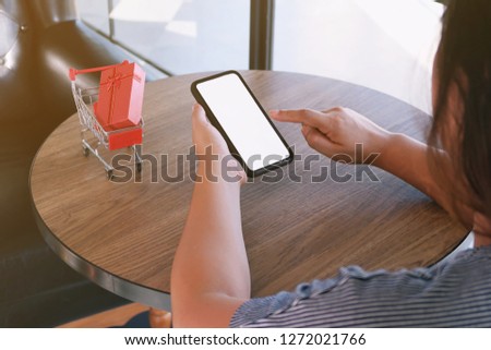 Woman and Small shopping cart with smartphone for Internet online shopping concept 
