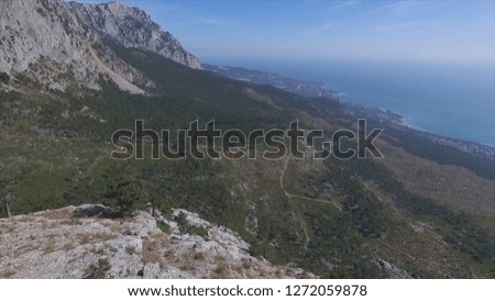 Aerial view from mountain peak - beautiful landscape with forest, sea shore and blue sky background. Shot. Mountain sea coast town panoramic landscape. Mountain sea town top view. Mountain sea coastal