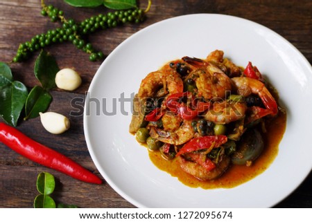 Close up Stir fried red curry with shrimp on wooden table with spicy herbs prepare for serving  i, Thai traditional food image for food and drink background , selective focus.