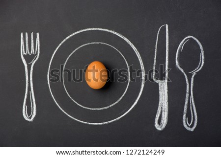 Boiled beautiful chicken eggs on a plate in the figure on a chalk board