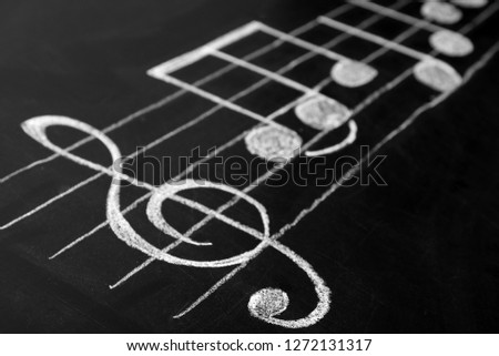 Music scale with treble clef and notes on chalkboard, closeup