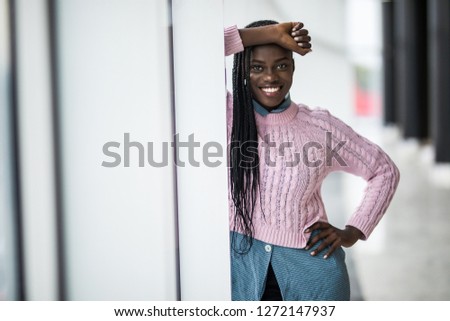 Young relaxed afro american woman smile standing on panoramic windows background