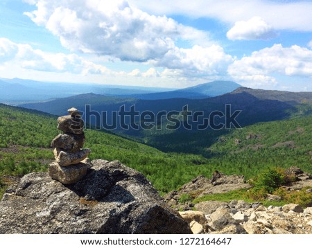 Pyramid of stones against the backdrop of a mountain pass. Stack of stones. View of the valley in the mountains