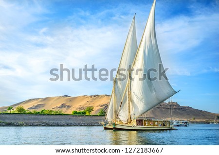 A traditional boat sailing through the Nile River in a late afternoon in Egypt