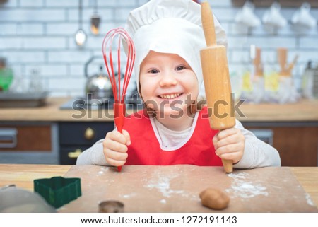 Cooking is fun. Little chef girl playing with flour. Young girl working on dough with rolling pin to make gingerbread biscuits