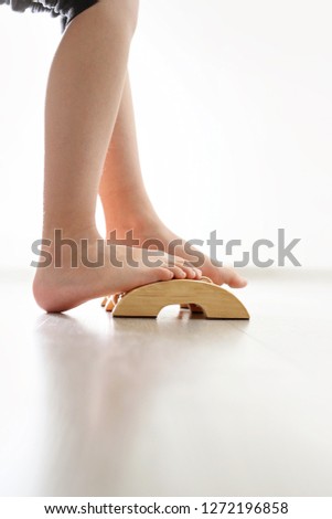 Foot massage. Feet of a child during a massage with a foot massage device on a wooden floor background.