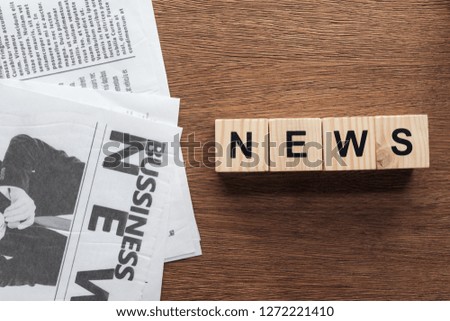 top view of wooden cubes with word news and business newspapers on wooden tabletop