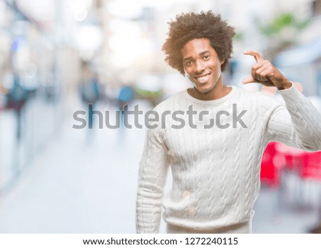 Afro american man over isolated background smiling and confident gesturing with hand doing size sign with fingers while looking and the camera. Measure concept.