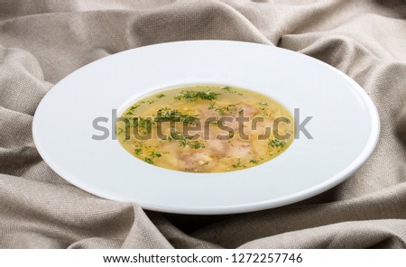 Chicken soup on a white plate on a textile background