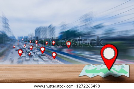 Map pointer icon placed on a wooden table, the background is blurred city streets and traffic jam,network concept covers all area,in urban and rural,using technology 4.0 find place to help travel 