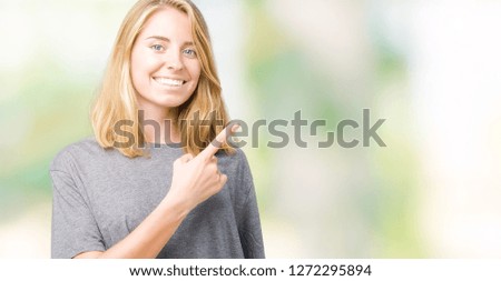 Beautiful young woman wearing oversize casual t-shirt over isolated background cheerful with a smile of face pointing with hand and finger up to the side with happy and natural expression on face
