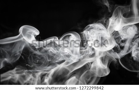 A thick waft of white smoke drifting over a black background/monochromatic smoke overlay or texture. 