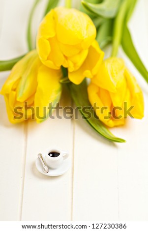 Tiny cup of coffee and yellow tulips