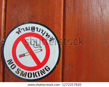 Warning sign for smoking and Thai language written in Ham sub boo ree on red wood