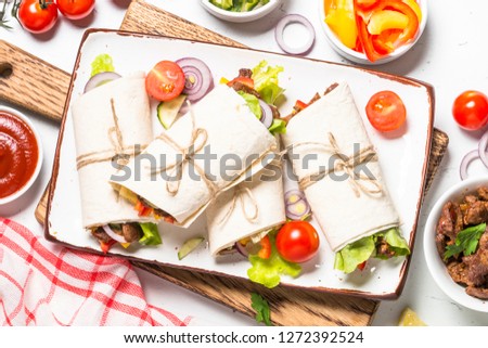 Burritos tortilla wraps with beef and vegetables on white background.  Mexican cuisine, latin american food. Top view.
