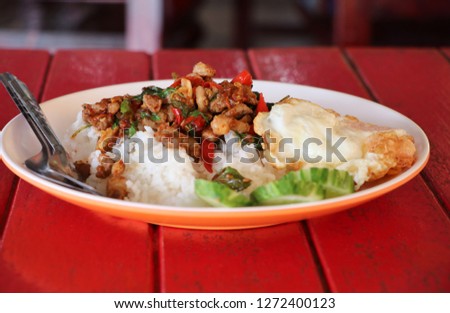 Rice topped with stir-fried duck and basil with spoon and fork  delicious for good lunch Asian food on red table background