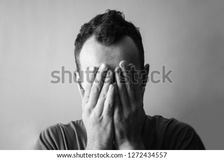 man from grief and sadness covers his face with his hands, black and white photo