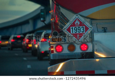 fuel tanker truck with safety flammable hazard sign 1993 in traffic on highway road at dusk