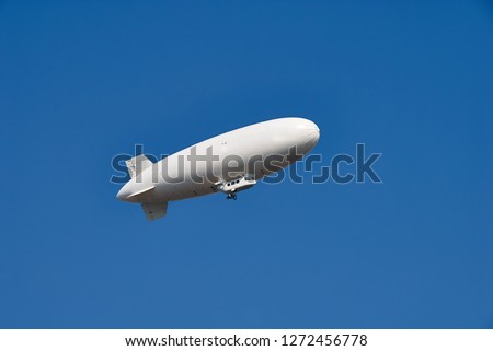 Large white dirigible airship against a clear blue sky. Plenty of room for text. Royalty-Free Stock Photo #1272456778