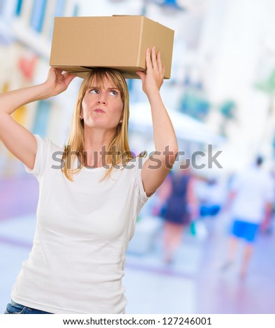 woman holding a box on her head against a street background