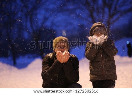 father and child playing with snow in a park fun season winter