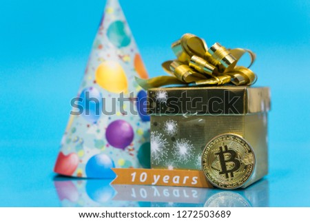 Bitcoin 10 year anniversary, coin with birthday golden present and birthday hat behind it and 10 years sign, copy space