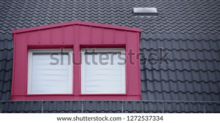 Selectively colorized photo of modern classic architecture fragment featuring tiled roof and attic. Mansard or mezzanine with window in pink / magenta color.