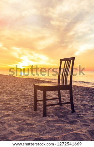 vintage wooden chair on sunset beach under warm light, Image for summer holiday vacation concept.