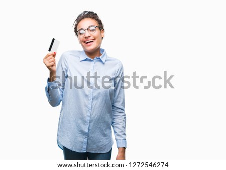 Young african american girl holding credit card over isolated background with a happy face standing and smiling with a confident smile showing teeth