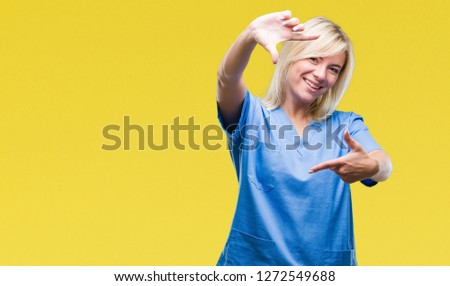 Young beautiful blonde nurse doctor woman over isolated background smiling making frame with hands and fingers with happy face. Creativity and photography concept.