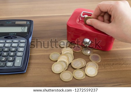 accumulate for poor people or investment .coins,hand ,calculator and red moneybox on the white background for charity foundation concept.person throwing money into piggy bank