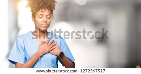 Young african american doctor woman over isolated background smiling with hands on chest with closed eyes and grateful gesture on face. Health concept.