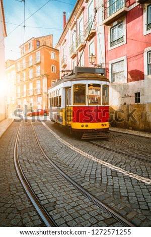 Touristic vintage red tram in a Lisbon street on sunny afternoon, narrow streets, cobblestones winding road, vacation in Lisbon. Royalty-Free Stock Photo #1272571255