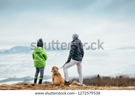 Father with son and dog look together on winter mountain city panorame 