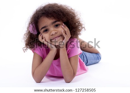 Relaxed little girl, looking at camera with her face in her hands.