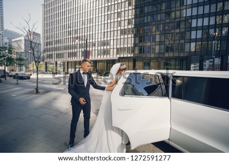 Elegant bride in a white dress and veil. Handsome groom in a blue suit. Couple in a big town