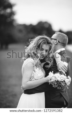 Beautiful bride in a long white dress. Handsome fiance in a blue suit. Couple in a summer park