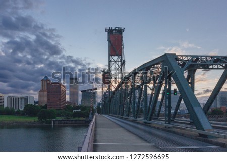 View of Hawthorne Bridge over Willamette River at sunset with skyline of downtown Portland, USA