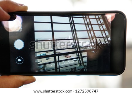 Phone in the hands of a tourist photographing the plane at the airport.