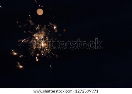 Closeup shot of a beautiful sparkler glowing on a dark bluish background