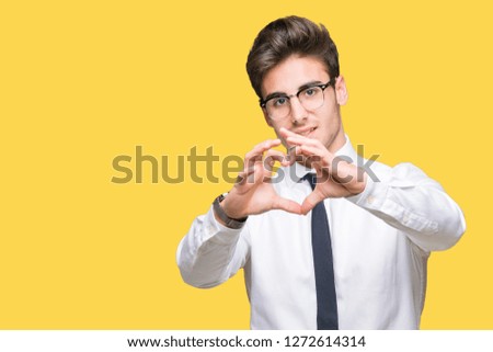Young business man wearing glasses over isolated background smiling in love showing heart symbol and shape with hands. Romantic concept.