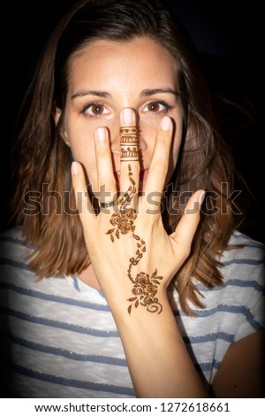 tourist woman showing her fresh made henna tattoo on her hand at night