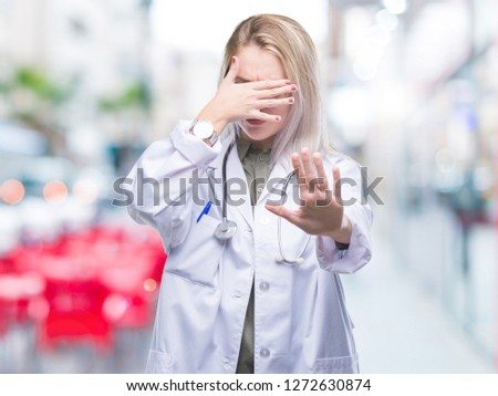 Young blonde doctor woman over isolated background covering eyes with hands and doing stop gesture with sad and fear expression. Embarrassed and negative concept.
