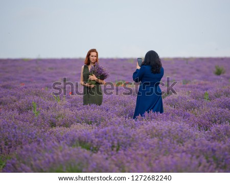 Two girls take pictures of each other in a lavender field.