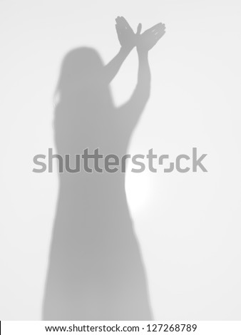 female body silhouette creating a shape of a flying bird with her hands, behind a diffuse surface Royalty-Free Stock Photo #127268789