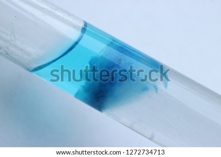 The chemical reaction of obtaining an insoluble precipitate of copper silicate in the form of a layer in a test tube at an angle. Royalty-Free Stock Photo #1272734713