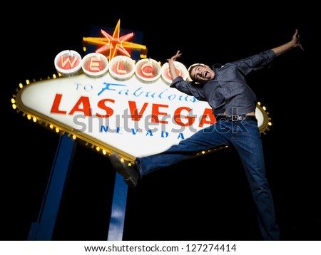 Low angle view of a young man jumping in front of a welcome sign,Las Vegas,Nevada,USA