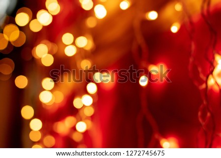 Red bokeh blurred lights background. Golden garlands decoration for the new year celebration.